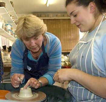 Sandy Larkman at work in her pottery teaching a student a new technique.